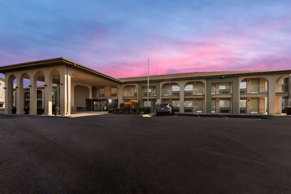 A hotel with a central courtyard, multiple balconies, and a parking lot.