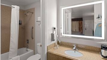 A bathroom with a bathtub, toilet, sink, and a large mirror.