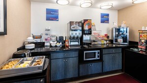 A self-service breakfast area with various food options, a coffee machine, and a microwave. - Best Western Executive Inn (Grove City)
