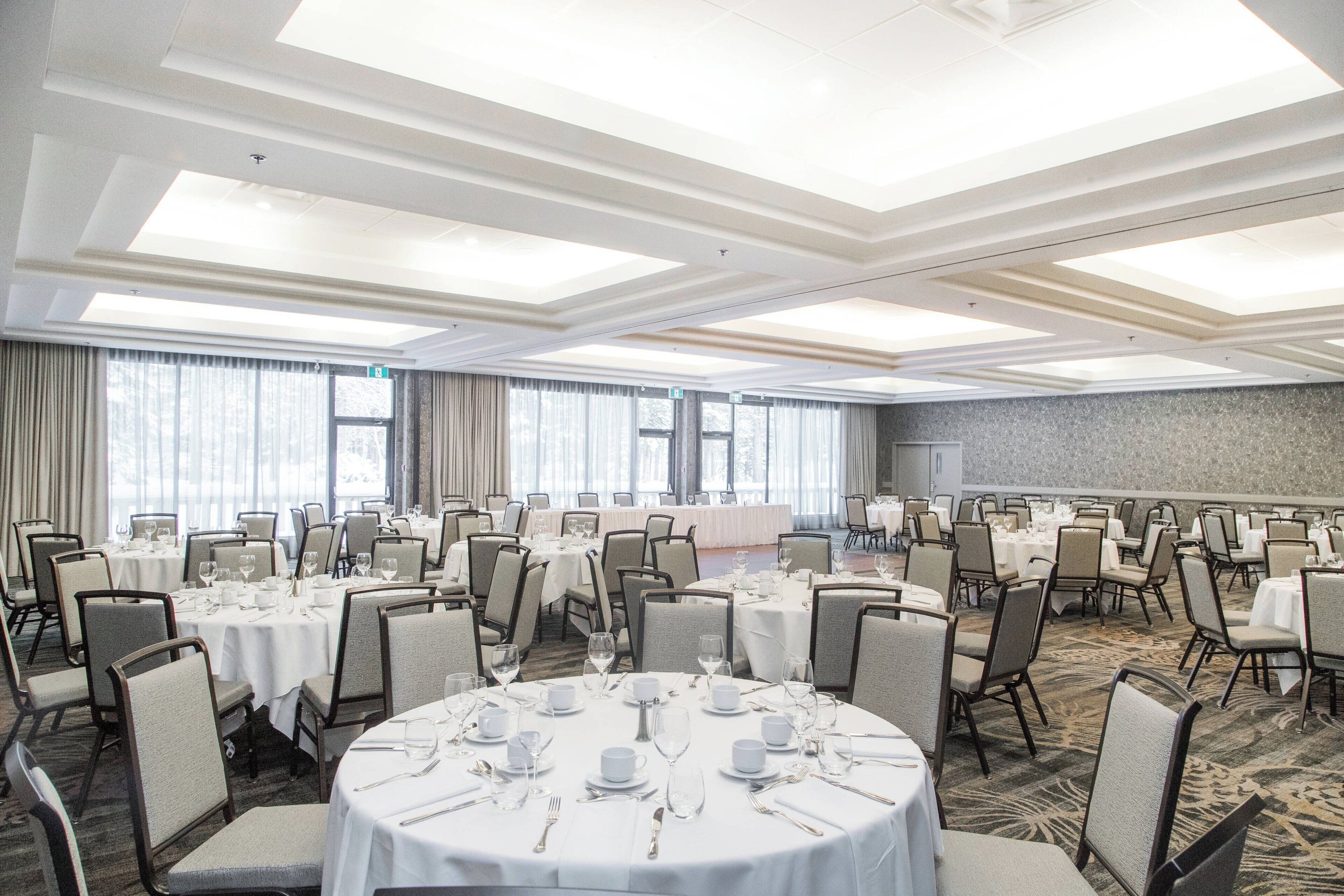 Un amplio salón de banquetes con mesas redondas dispuestas en filas para cenar, con sillas.