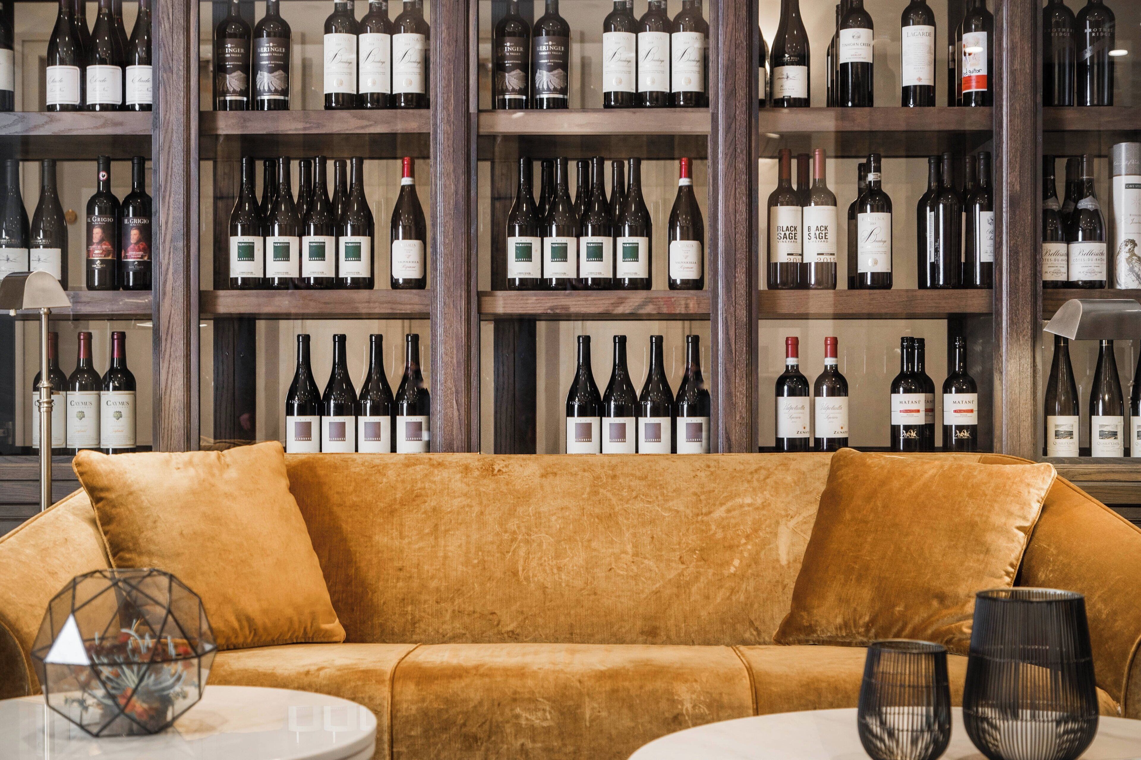 A wine cellar with shelves of wine bottles and a velvet sofa in the foreground.