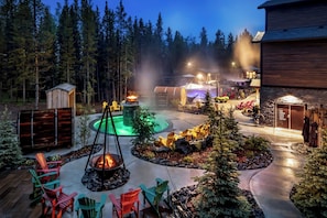 A well-lit outdoor patio area with a fire pit, seating, and a pool. - Kananaskis Mountain Lodge, Autograph Collection (Kananaskis)