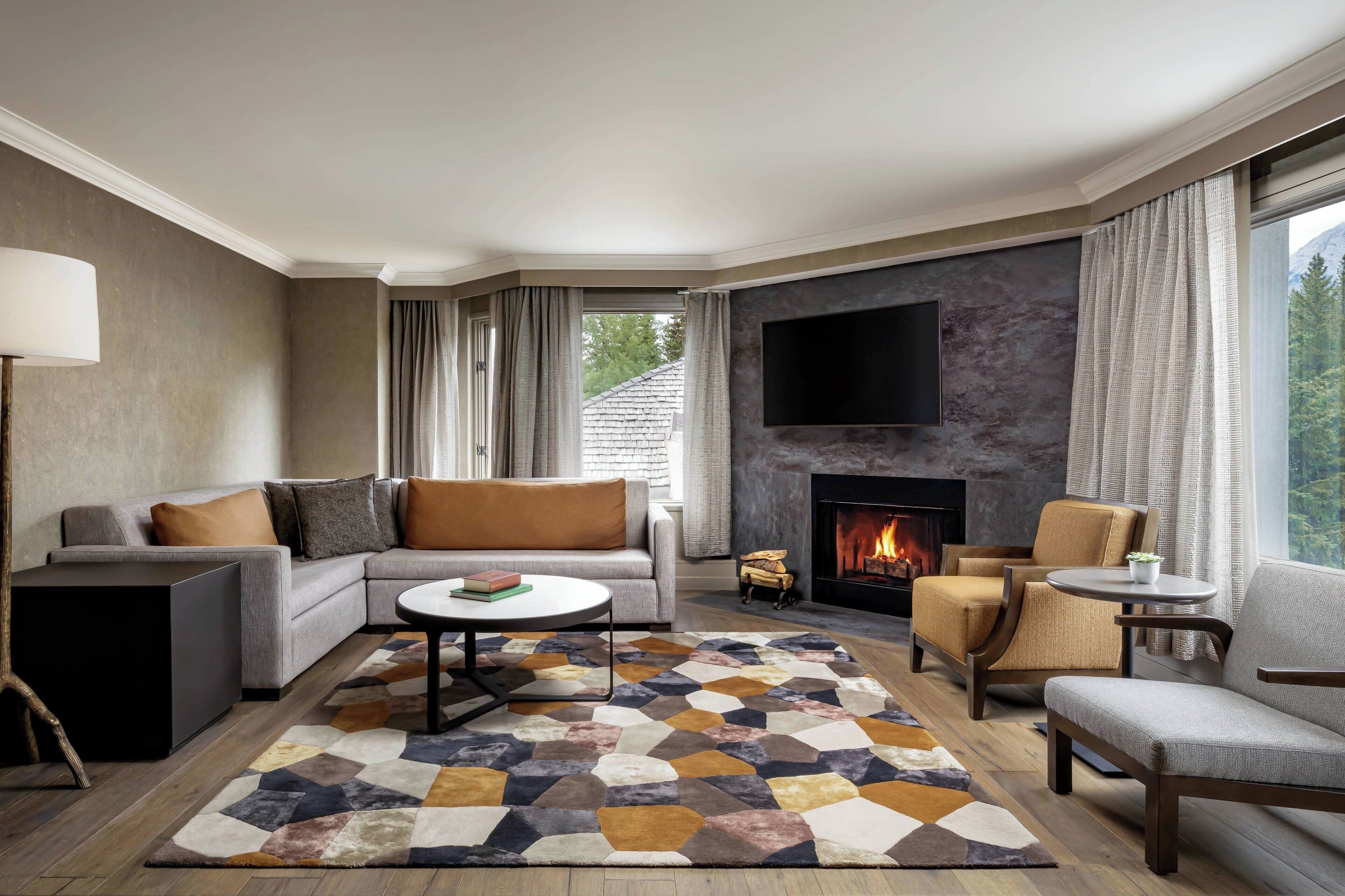 A modern living room with a fireplace, a flat-screen TV, and a large window with curtains.