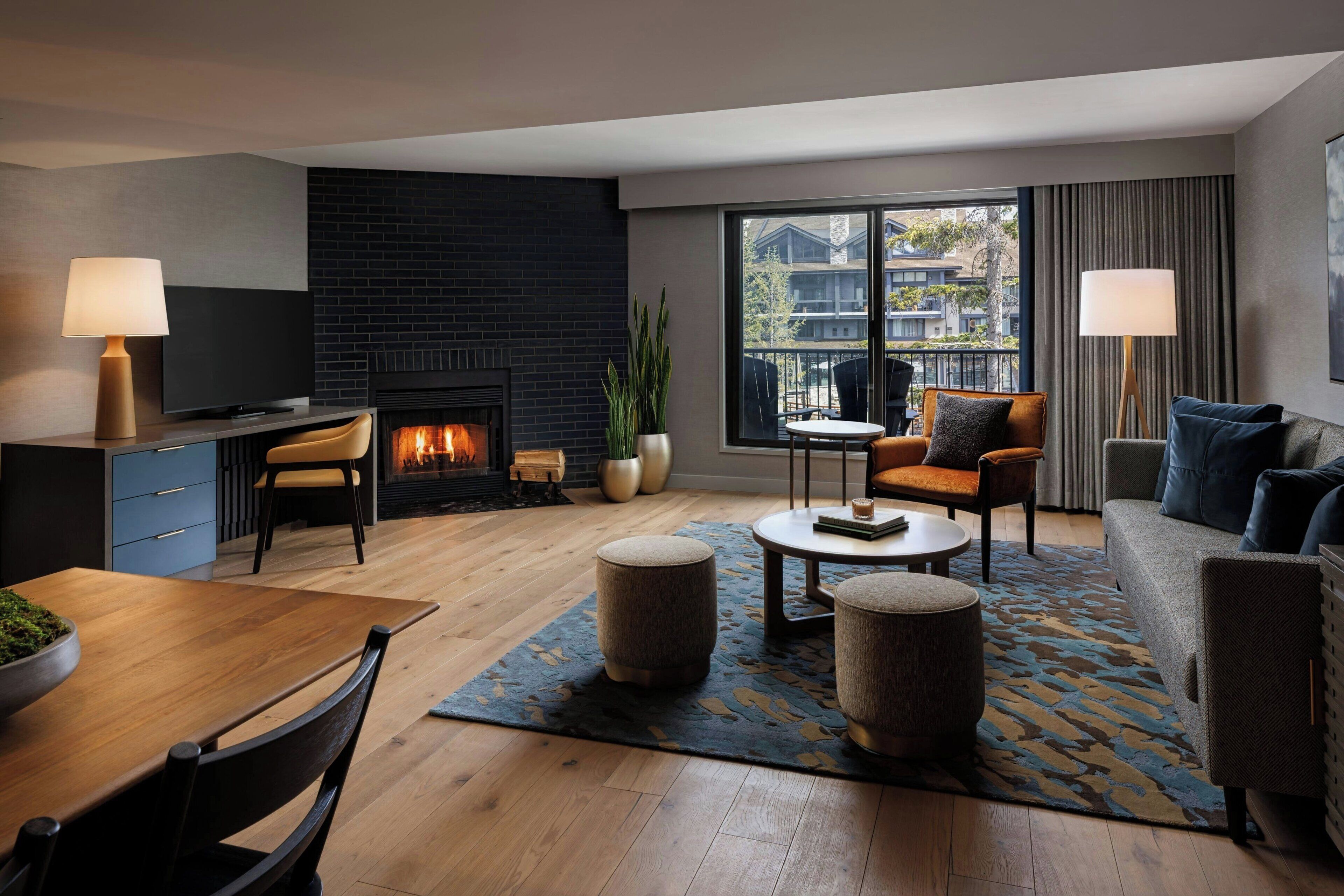 A modern living room with a fireplace, a dining area, and a sofa set.