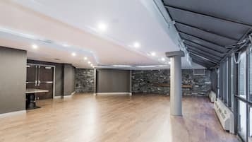 Una habitación amplia con piso de madera, una pared decorativa de piedra y un tragaluz.