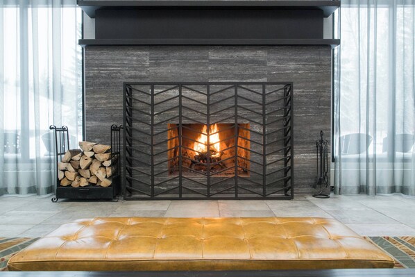 Cozy up by the fireplace, surrounded by a geometric metal design and a tufted leather bench.