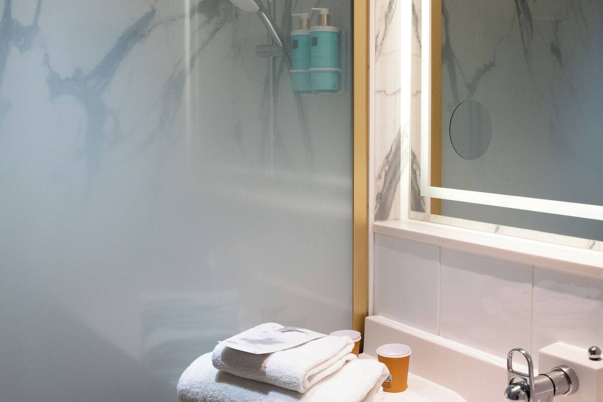 Une salle de bain moderne avec une douche à parois de verre, un lavabo blanc et un miroir au-dessus.