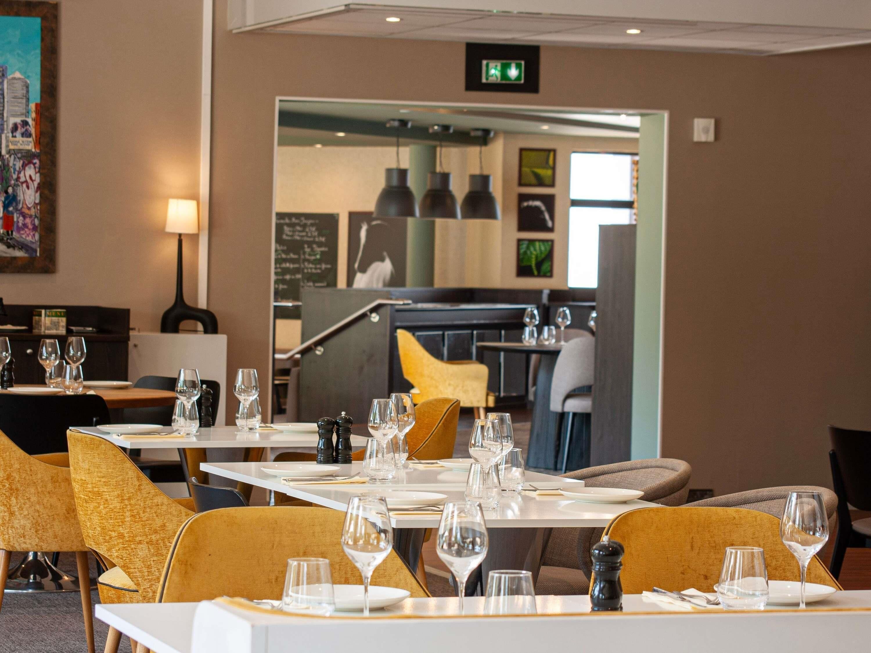 A restaurant interior with tables set for dining, chairs, and a visible exit sign.