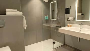 A modern bathroom with a glass-enclosed shower, a white sink, and a large mirror.