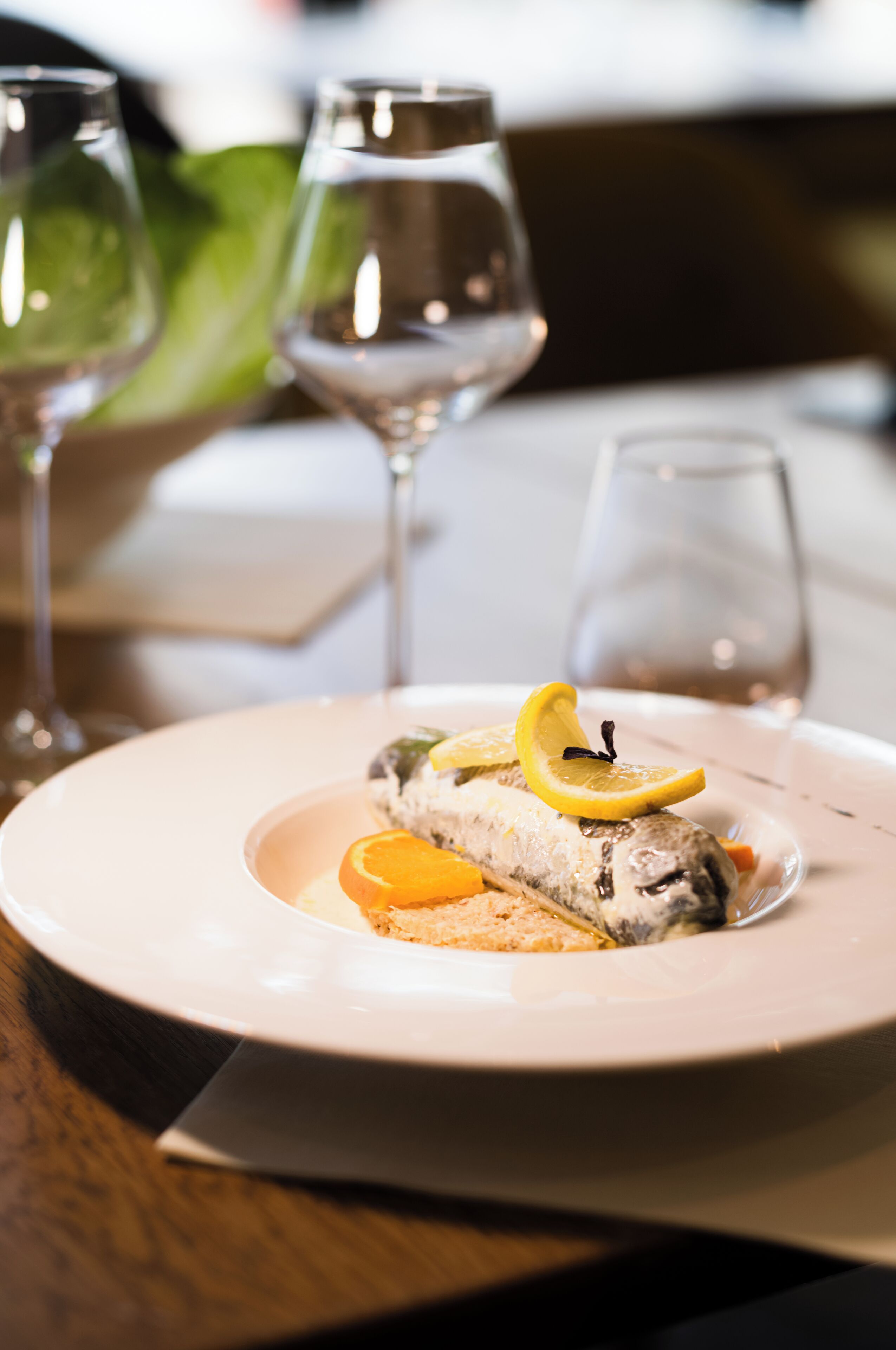 Un plato con guarnición de pescado, un vaso de agua y una copa de vino sobre una mesa.