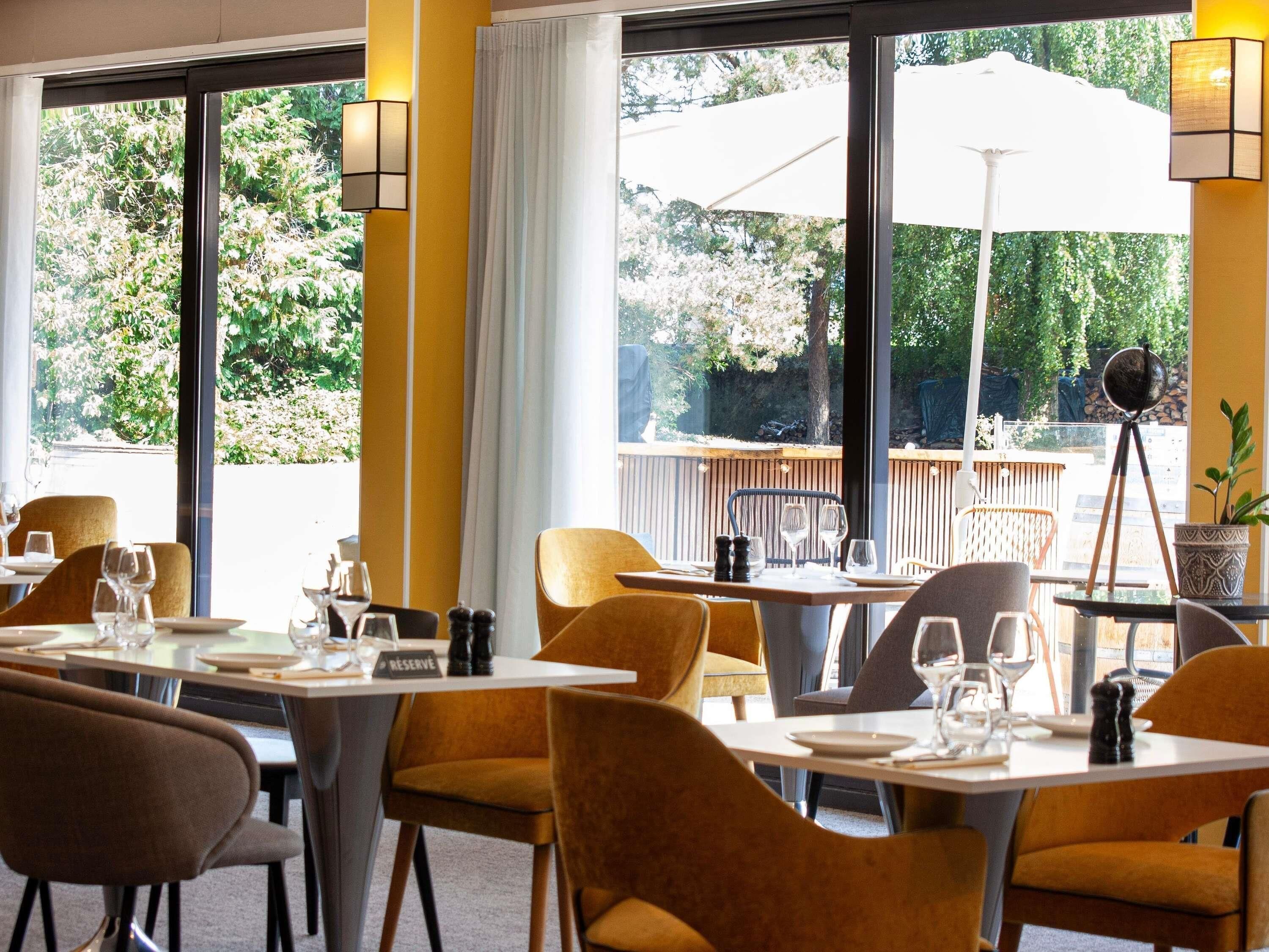 Un restaurante con mesas y sillas, un letrero que indica una mesa reservada y vistas a zonas verdes al exterior.