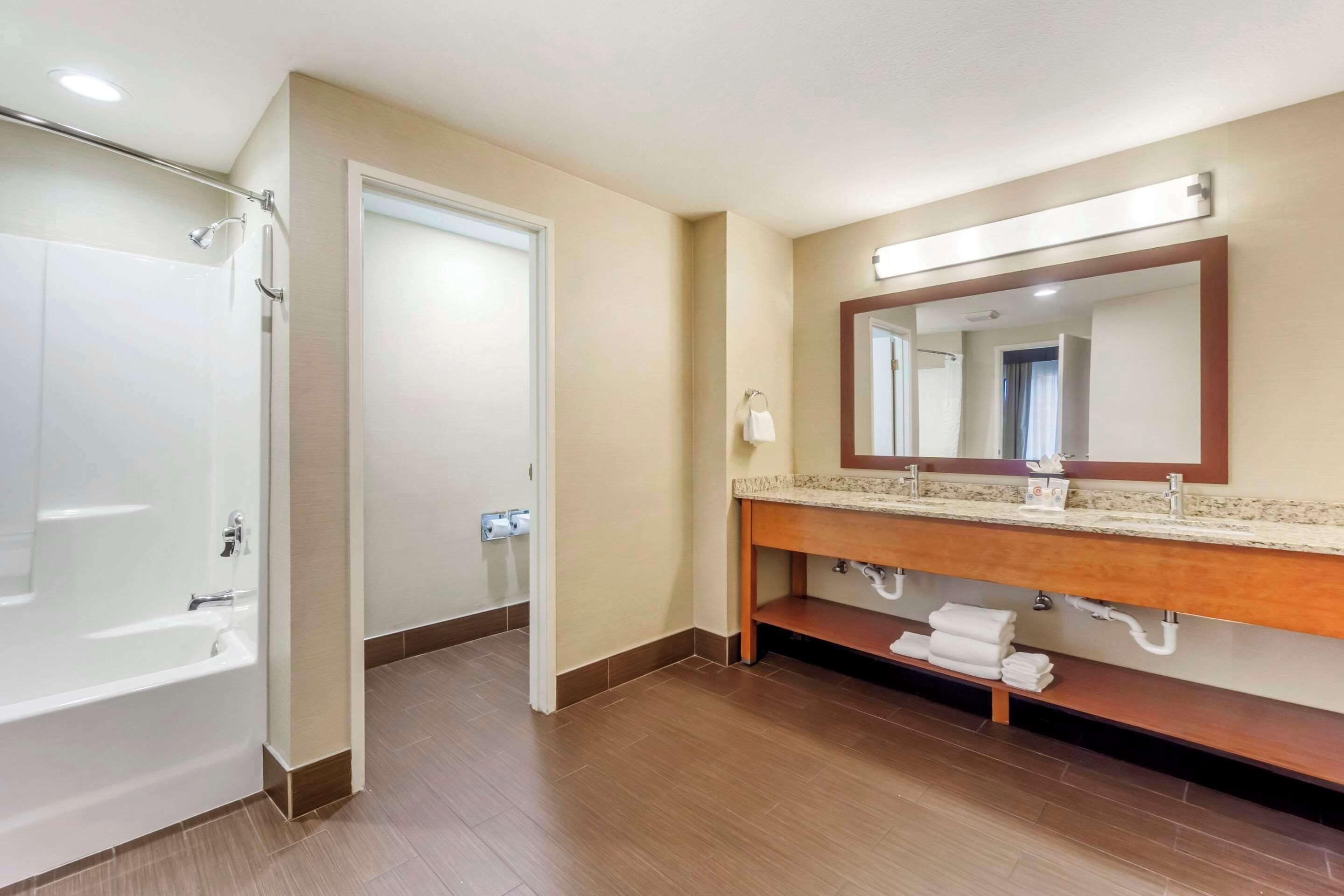 Ein modernes Badezimmer mit einer Badewanne, einem großen Spiegel und einem Waschtisch mit einer Arbeitsplatte.