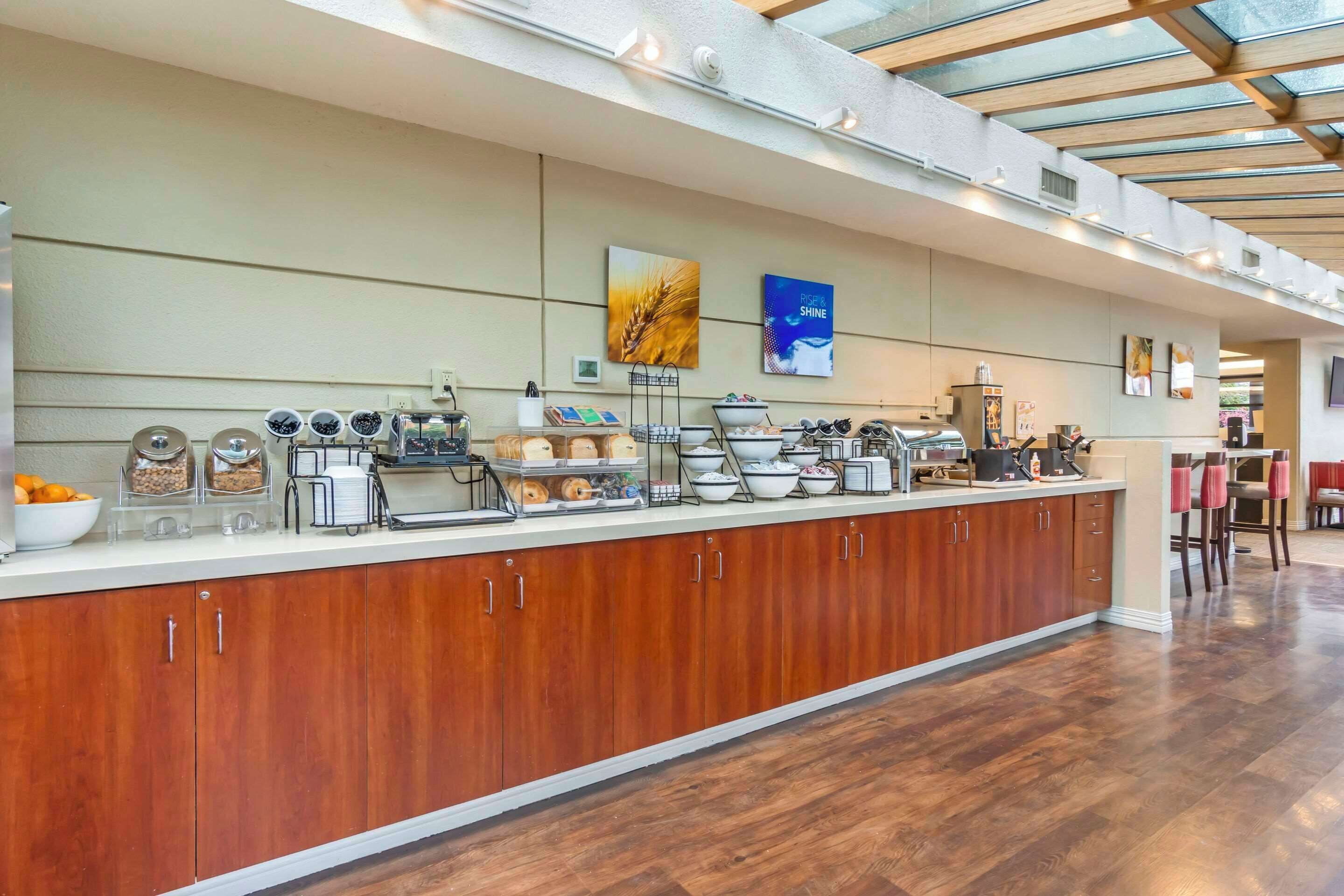 A modern kitchen with a wooden counter, various food items, and two wall art pieces.