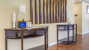 A reception area with two dark wooden tables, a digital thermostat, and a decorative wall panel. - Comfort Inn & Suites Sea-Tac Airport (SeaTac)