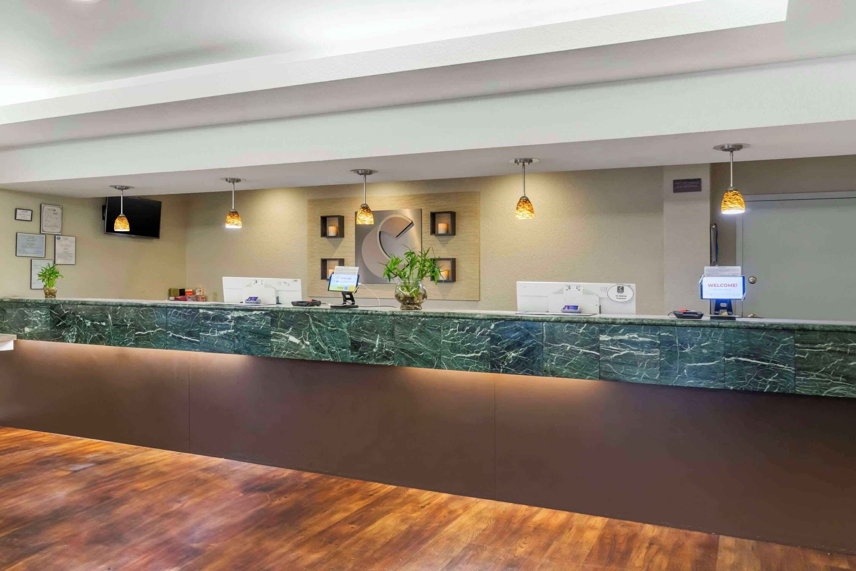 A reception area with a marble counter, framed certificates, a welcome sign, and a television.