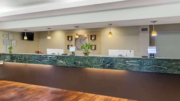 A reception area with a marble counter, framed certificates, a welcome sign, and a television.