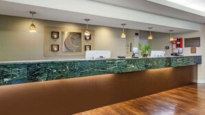 A reception area with a marble counter, pendant lighting, framed artwork, and a bulletin board. - Comfort Inn & Suites Sea-Tac Airport (SeaTac)