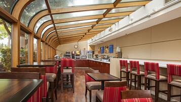 Un restaurant doté d’un plafond incurvé, de tables et de chaises en bois, et offrant une vue sur la verdure environnante.