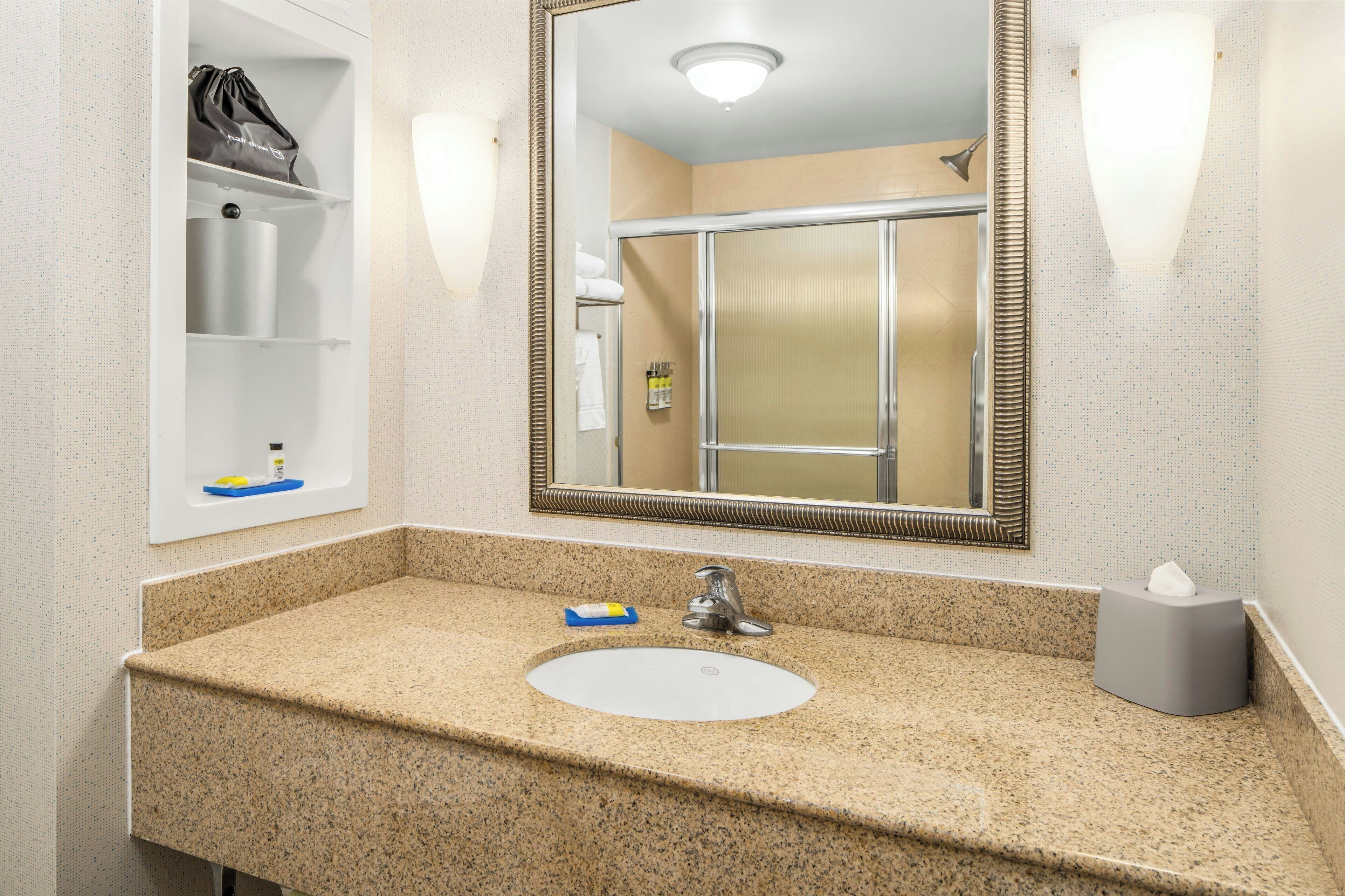 A bathroom with a sink, mirror, towel rack, and a shower.