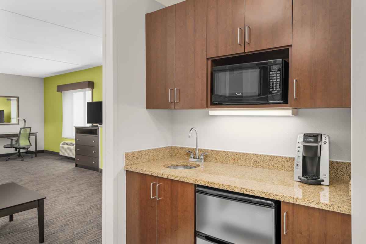 A kitchen with wooden cabinets, a stainless steel dishwasher, a microwave, and a coffee maker.