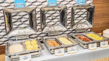 A buffet with labeled containers for sausage gravy, turkey sausage, scrambled eggs, bacon, and egg white & veggie omelet.