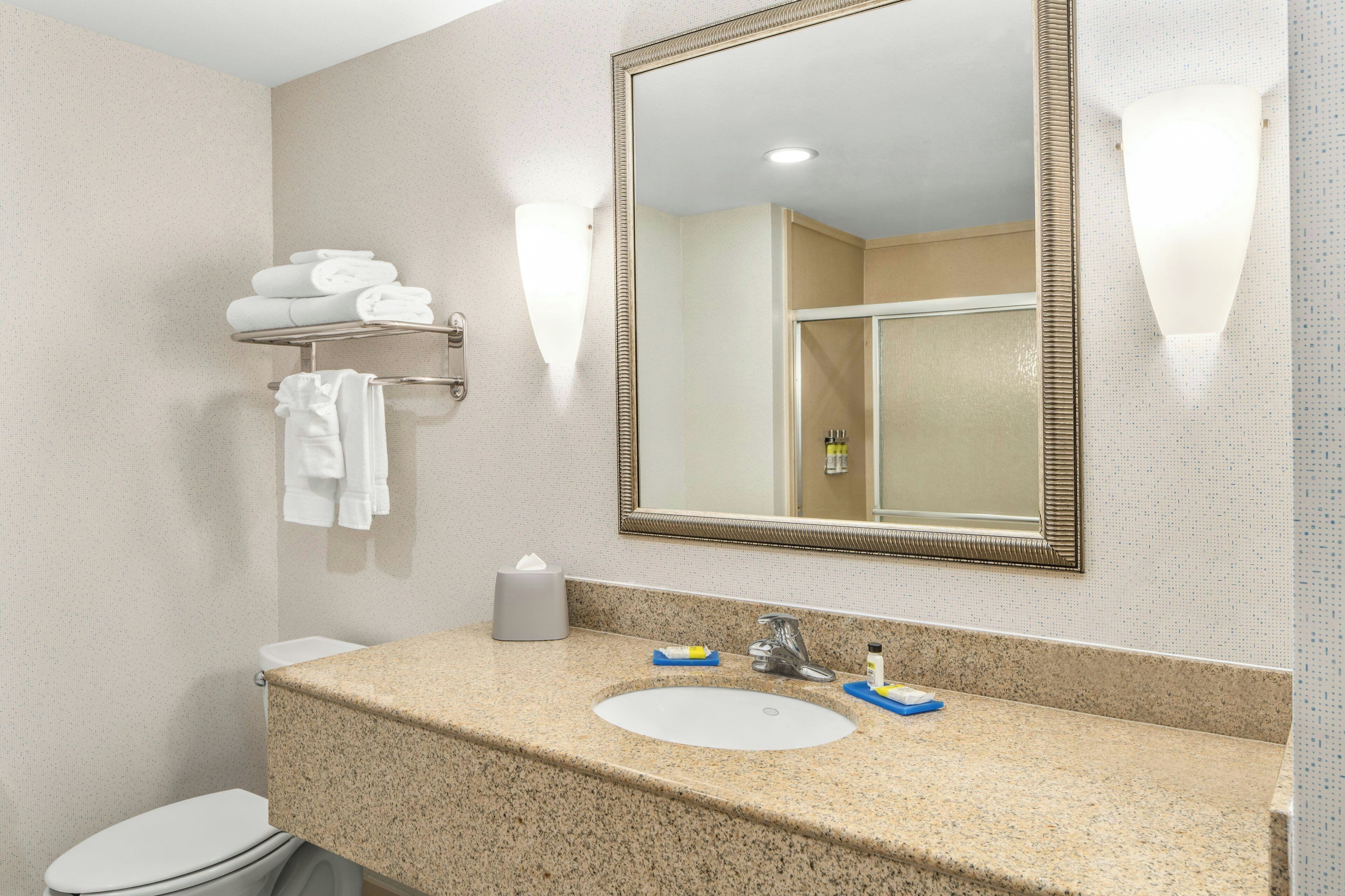 A bathroom with a sink, mirror, towel rack, and a toilet.