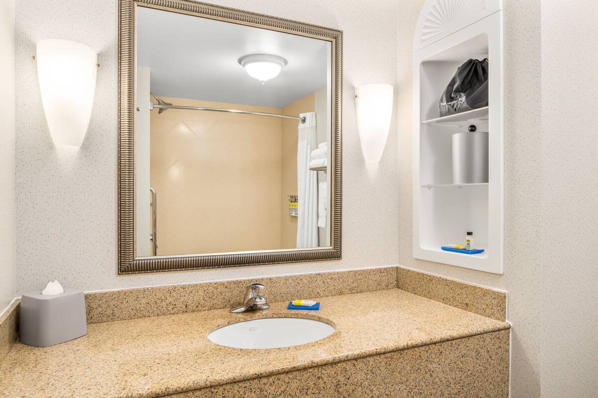 A bathroom with a large mirror, a sink, and a towel rack.