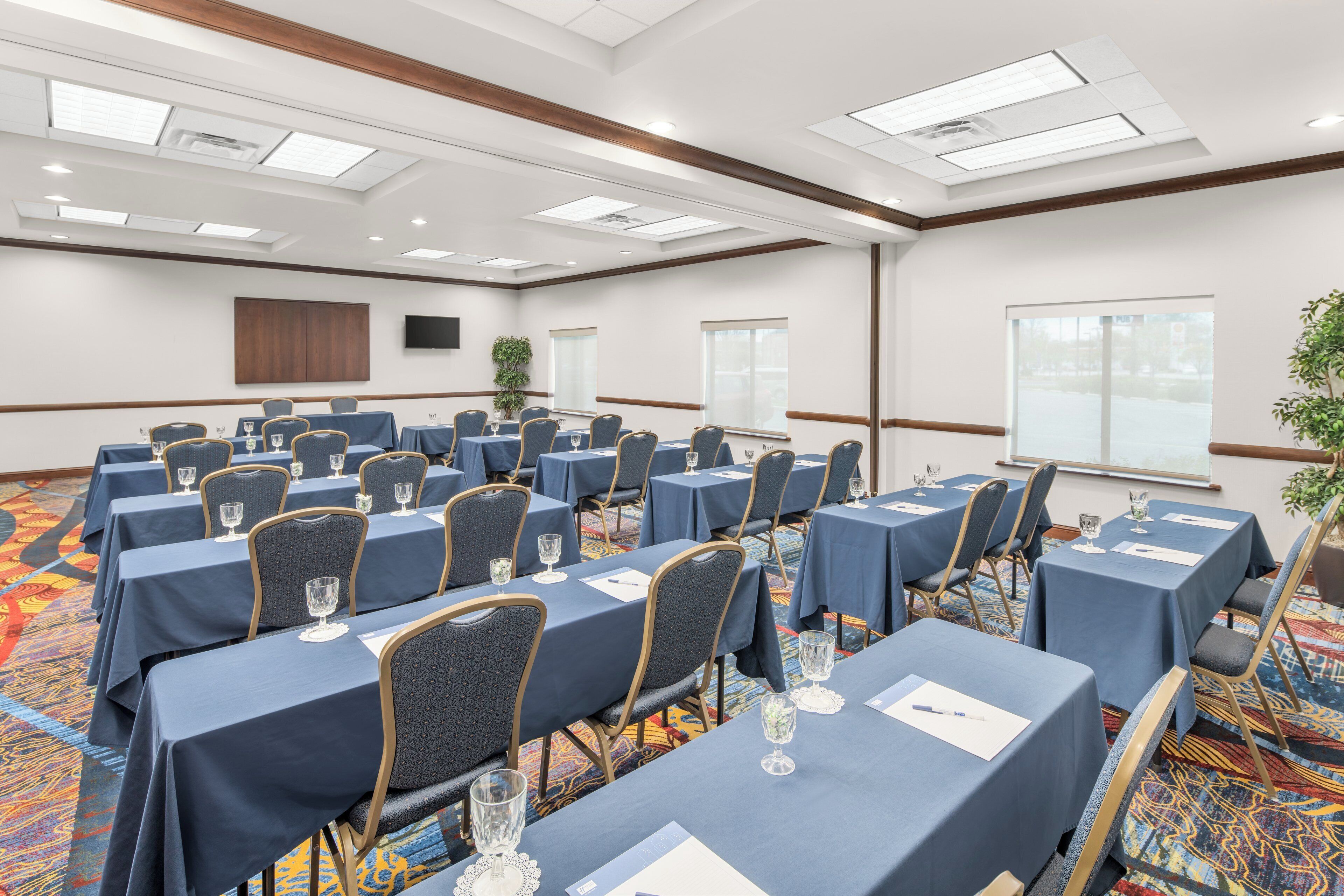 Une salle de conférence équipée de plusieurs tables, de chaises et d’une grande fenêtre.