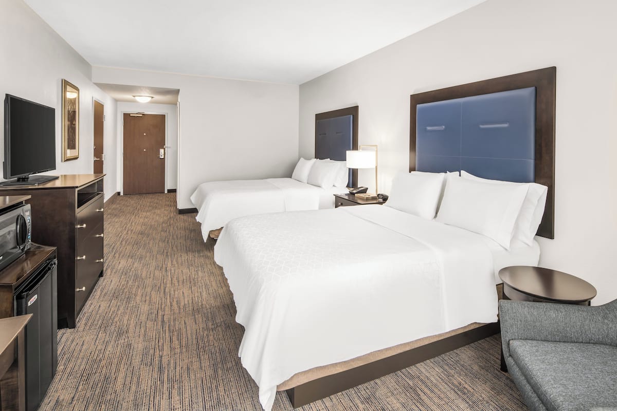A hotel room with a large bed, a desk with a television, and a small seating area.