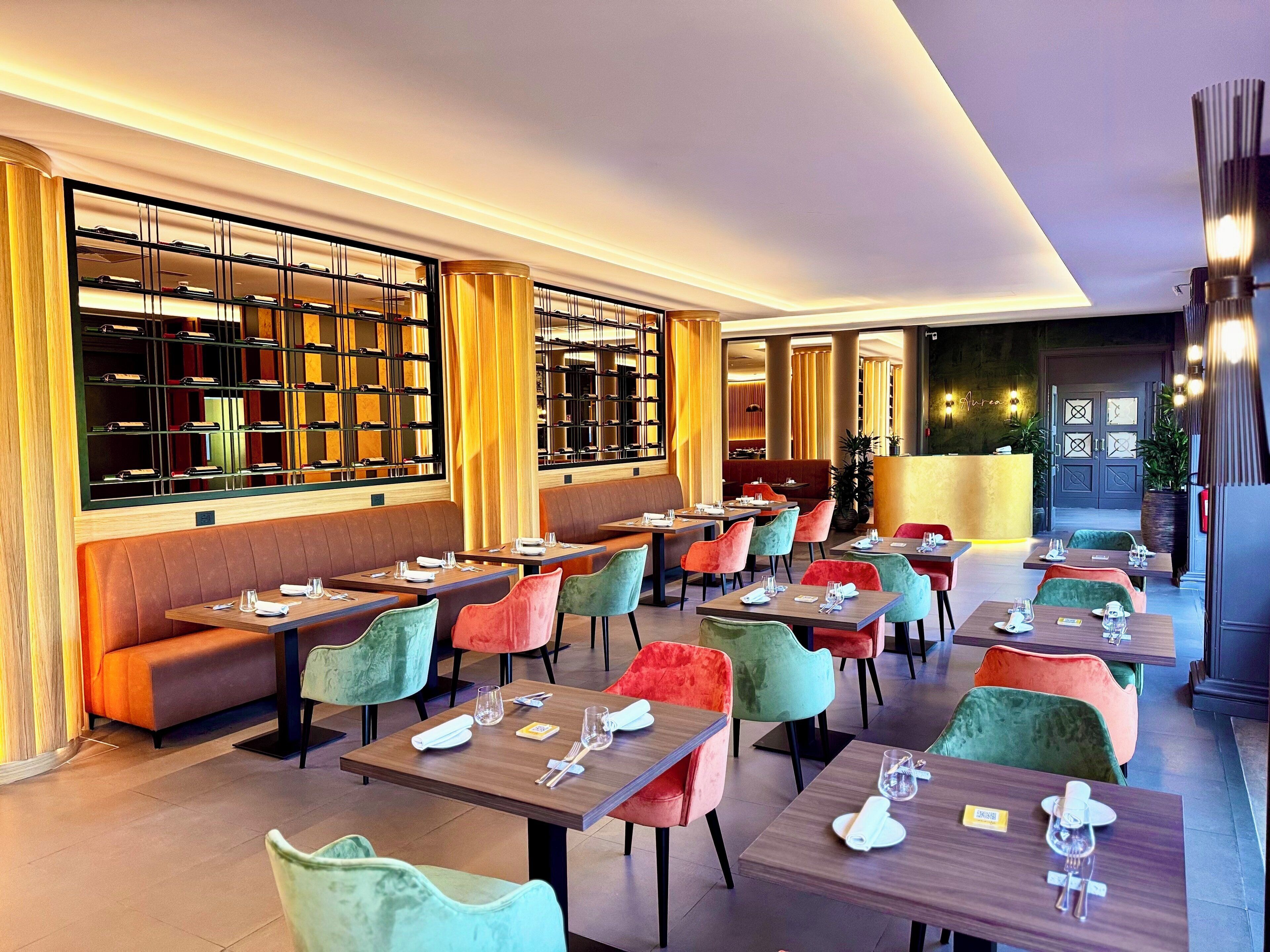 Un restaurant doté de nombreuses tables et de banquettes, chacune étant agrémentée d’une belle batterie de couverts.