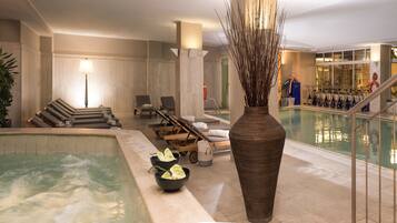 A spa area with a hot tub, lounge chairs, a large vase, and a pool.