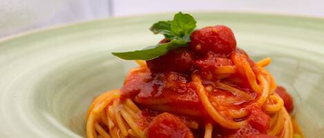 A plate of spaghetti with tomato sauce and a garnish.