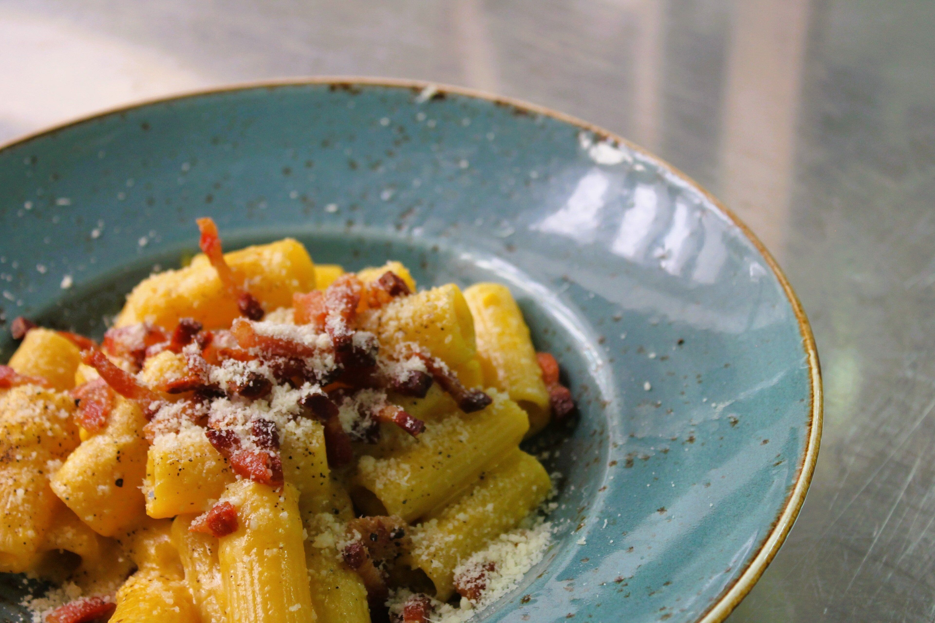 A plate of pasta with cheese and bacon.