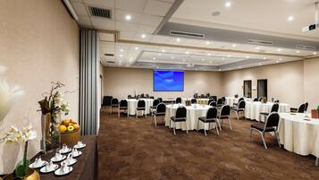 A conference room with round tables, chairs, and a projector screen.