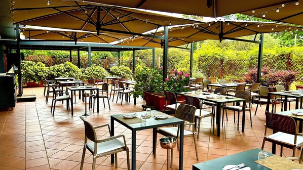 An outdoor patio with tables and chairs, surrounded by potted plants and a wooden fence. - Crowne Plaza Rome-St. Peter's Hotel & Spa by IHG (Rome)
