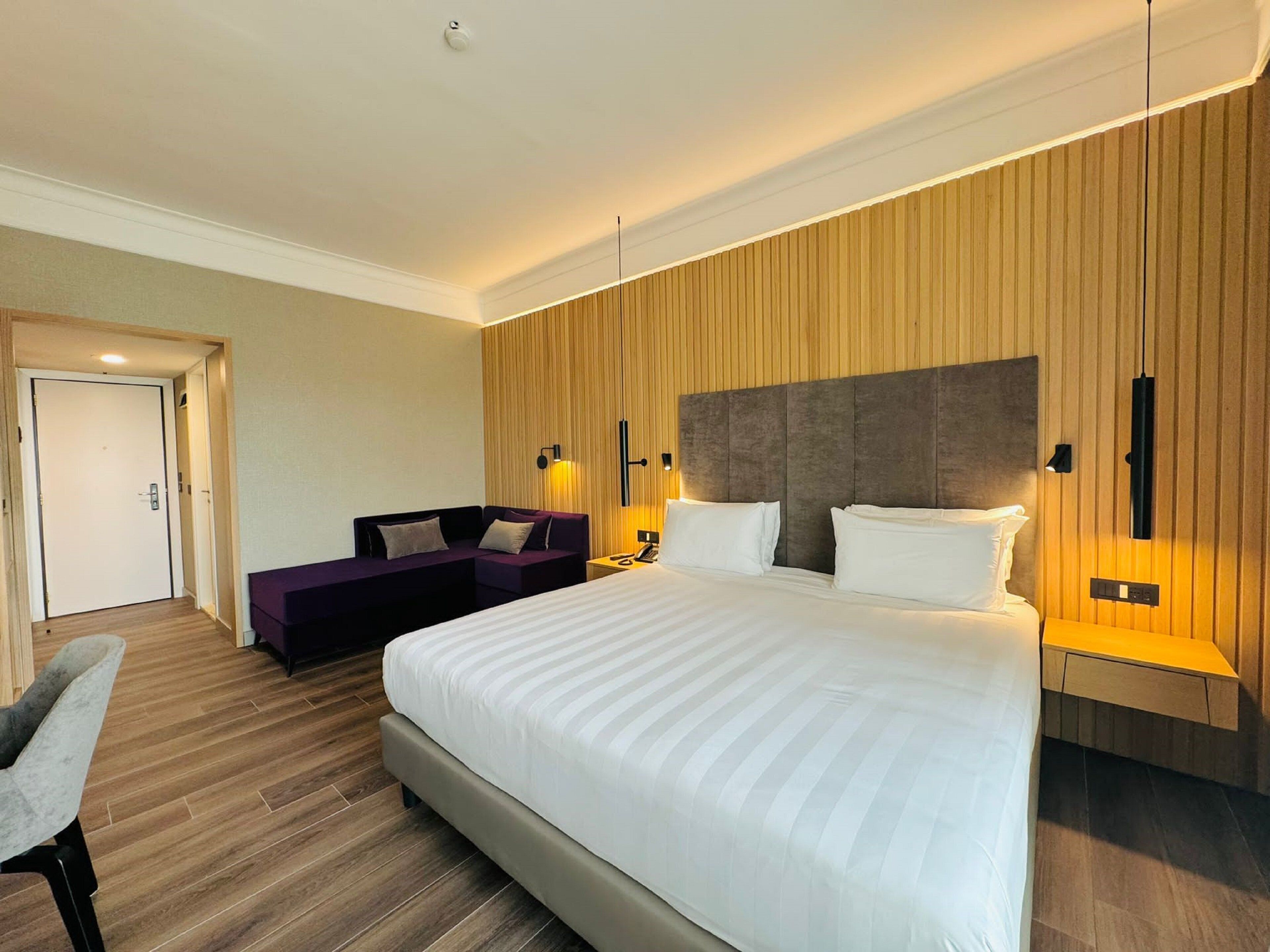 Een moderne hotelkamer met een groot bed, een bank en een bureau.