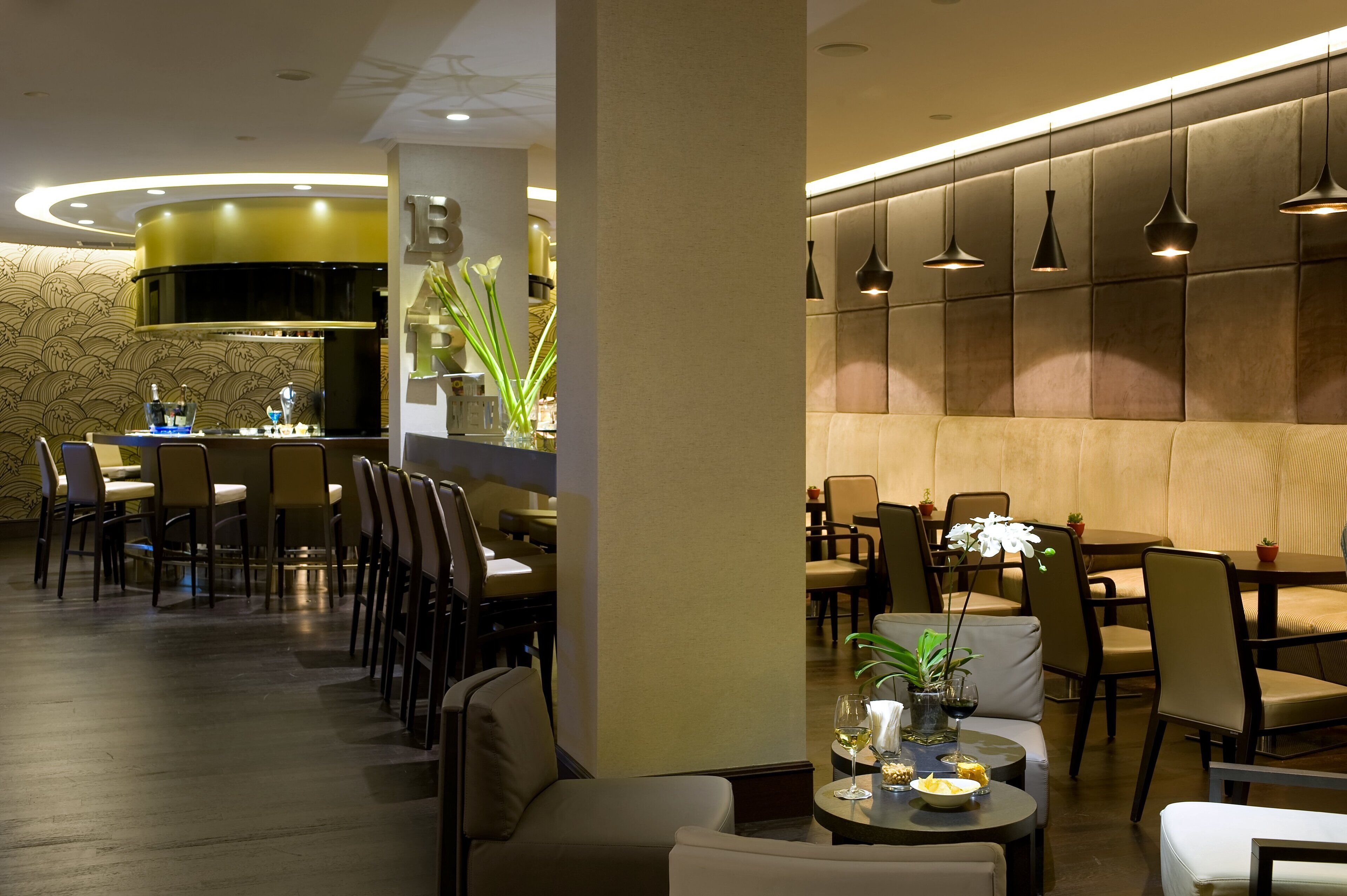 A modern restaurant with a central bar, seating arrangements, and ambient lighting.
