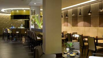 A modern restaurant with a central bar, seating arrangements, and ambient lighting.