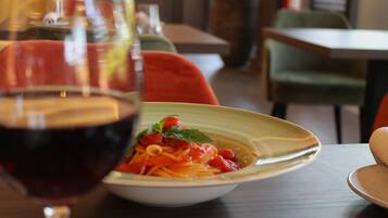 A dining table with a bowl of spaghetti and a glass of red wine.