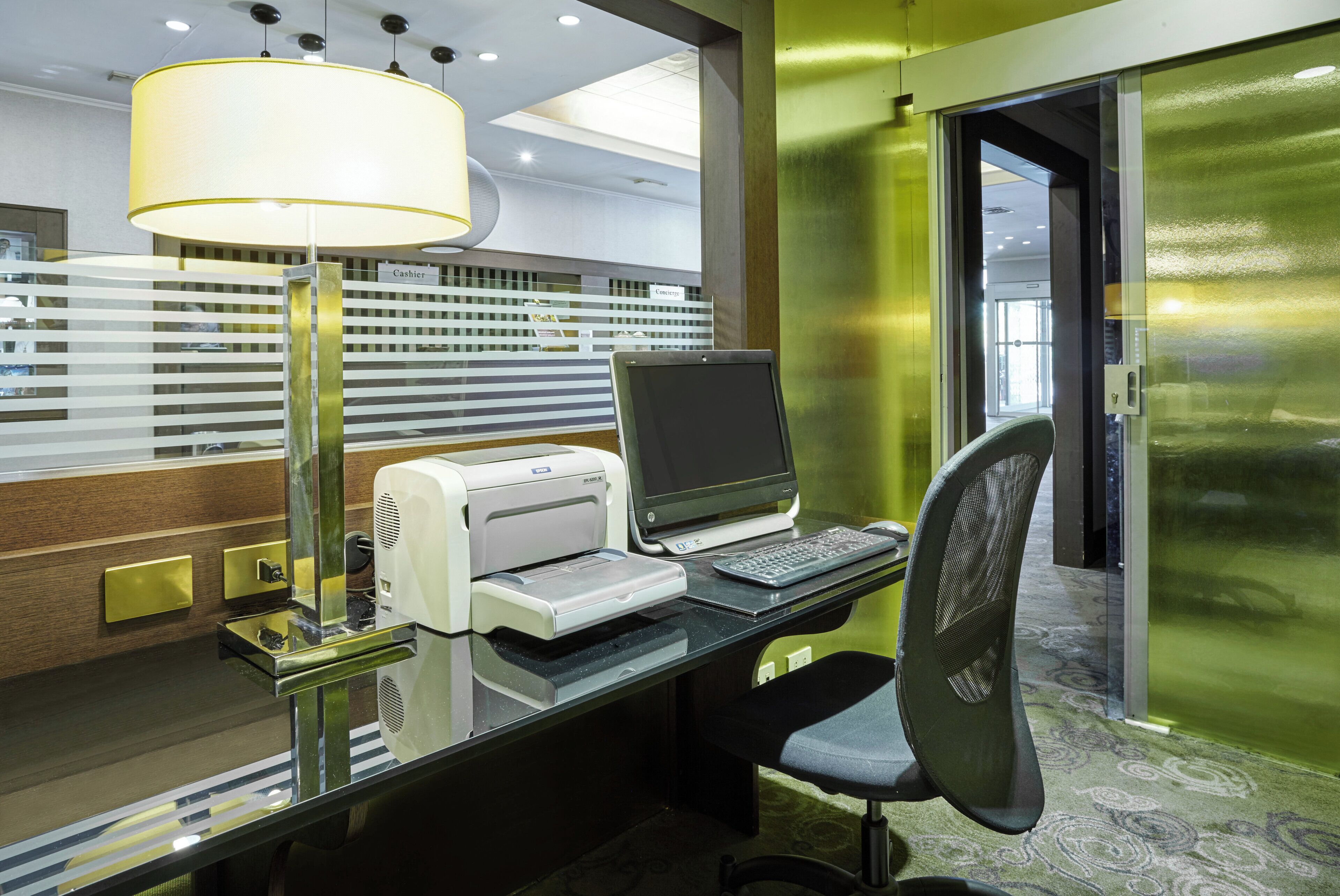 A modern office desk with a computer, printer, and lamp.