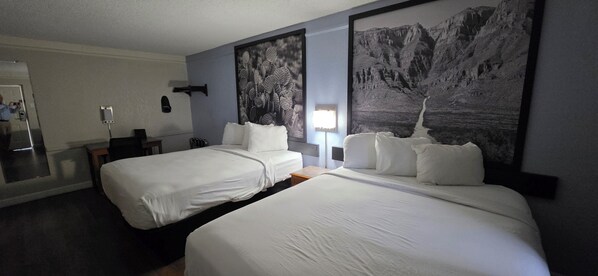 A hotel room with two beds, a desk, a chair, a mirror, and two large black-and-white landscape paintings on the walls. - Super 8 by Wyndham Austin South / I-35 (Austin)
