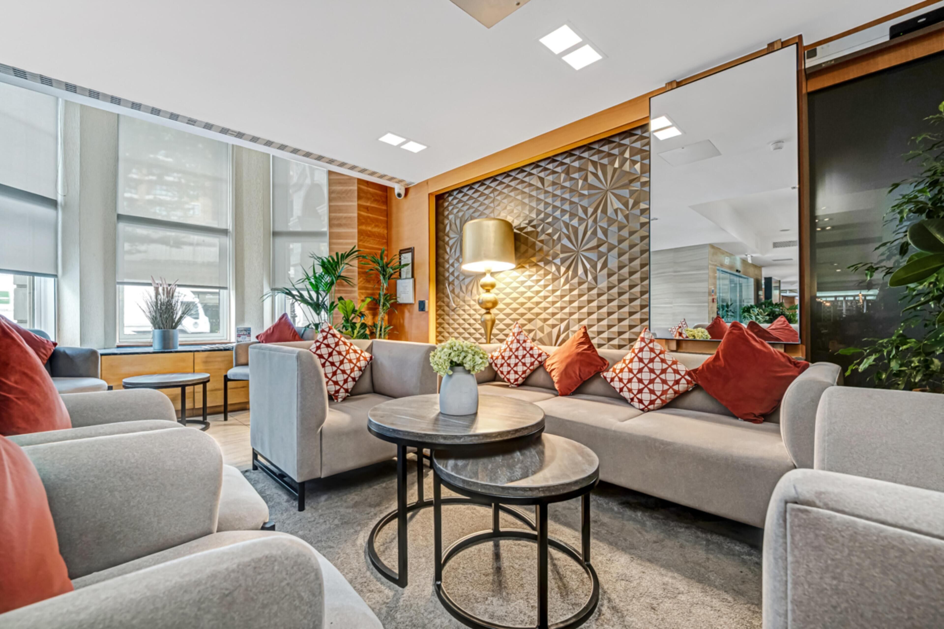 A modern lounge area with a sofa set, a round coffee table, and a decorative wall panel.