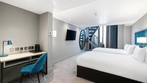 Une chambre d’hôtel avec un lit, un bureau, une chaise, une télévision et un escalier.