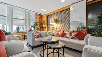 Een moderne zithoek met een bank, een rond salontafeltje en een decoratief wandpaneel.