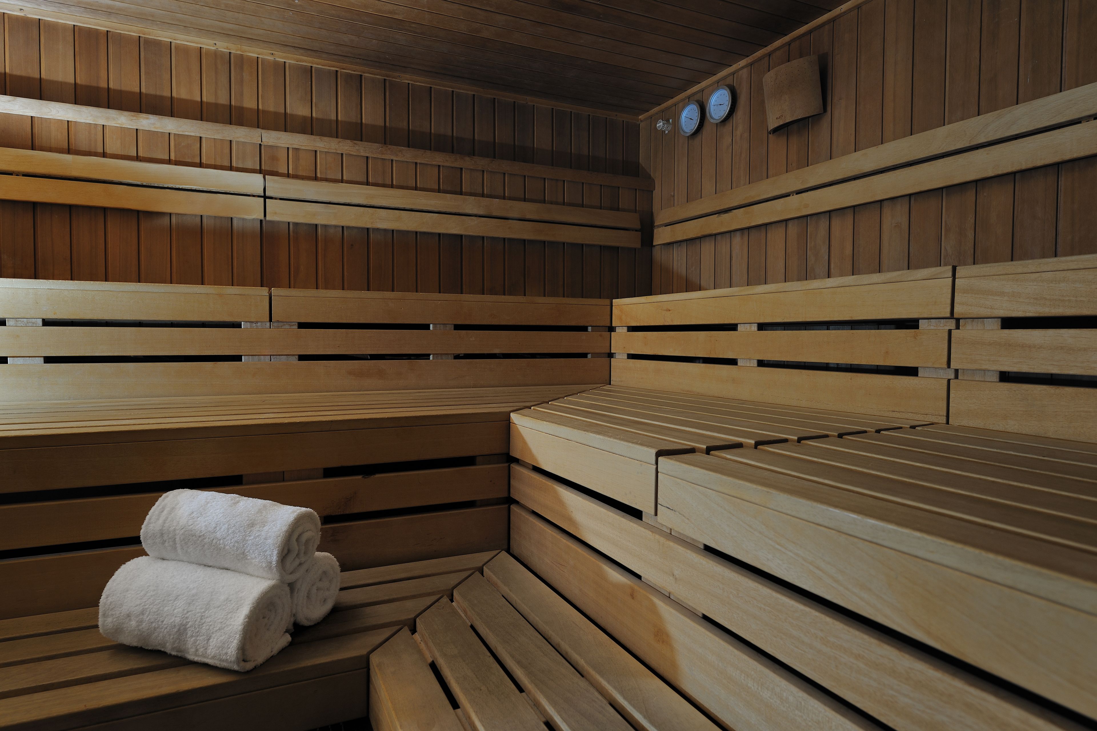 A sauna with wooden benches and a bench with towels.