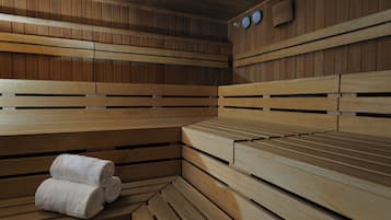 A sauna with wooden benches and a bench with towels.