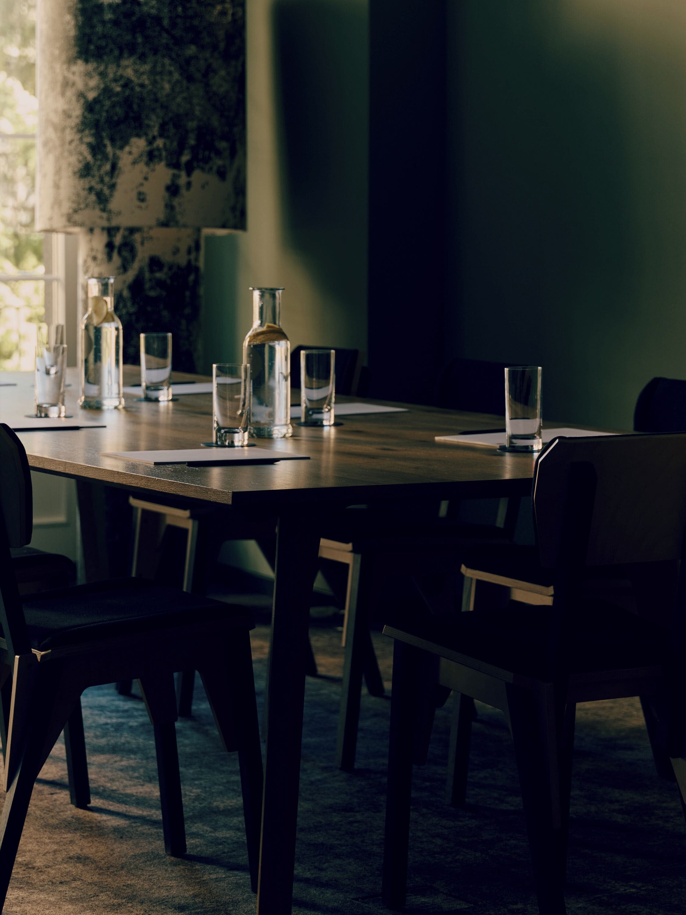 Una mesa de comedor con sillas, una botella y vasos.