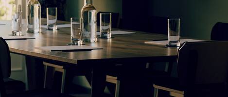 Una mesa de comedor con sillas, una botella y vasos.