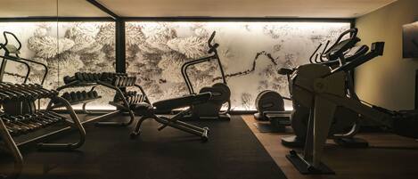 A gym with exercise equipment, a wall with a textured pattern, and a wooden floor.