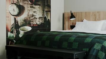 A bedroom with a bed, a bench, a wall-mounted lamp, and a wooden headboard.